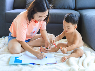 Obraz na płótnie Canvas Asian mom teaching her baby boy draw