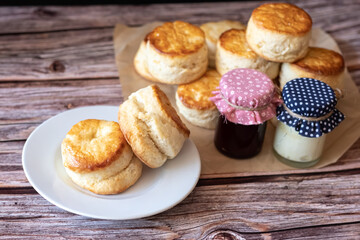 Traditional British Scones on white plate and Cream cheese, Cranberry jam in glass bottle on wooden table background. 