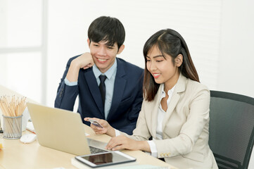 Fototapeta premium Asian staff holding credit card and using laptop computer in office. Online Shopping, internet banking, spending money
