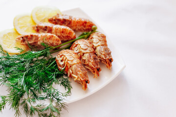 Shrimp on a plate with lemon and dill. White background