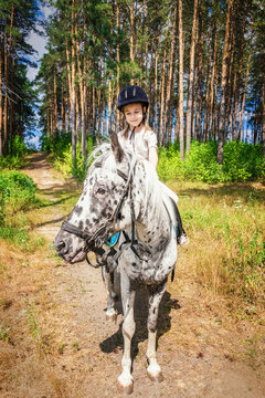 cute girl on a white horse with black spots