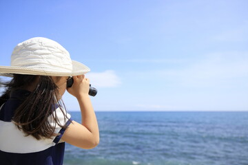 海辺でオペラグラスを使う幼児(5歳児)