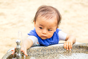 公園の水飲み場で真剣に水を飲もうとする子供　こまめに水分補給