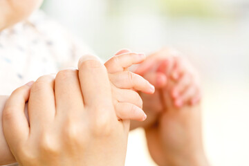 Obraz na płótnie Canvas 母親と赤ちゃんが手をつなぐ　両手をつなぐ親子の触れ合い