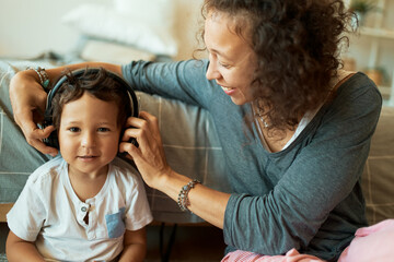 Attractive young mixed race mother babysitting her adorable three year old son, using wireless...