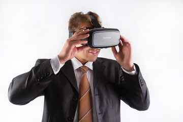 A male businessman in a black suit and tie wearing a virtual reality helmet see images, on a white background