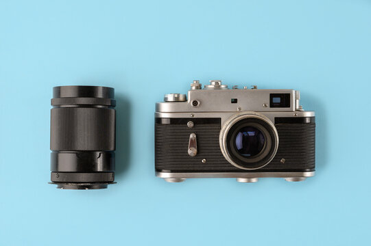 Retro photo camera with lens on blue background, top view