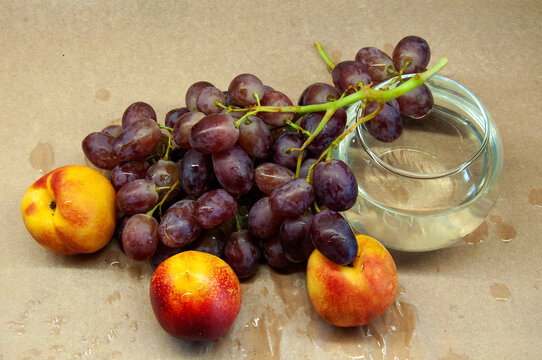 photo of a brush of grapes with nectarine with a glass on a beige background