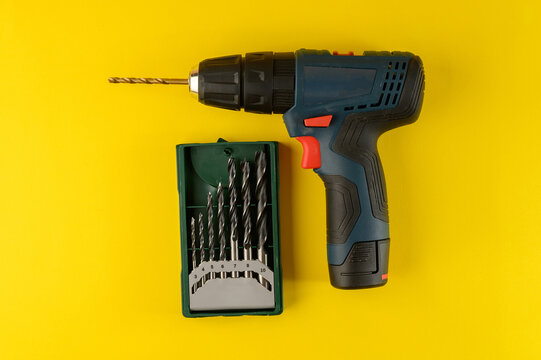 cordless drill, screwdriver with drill bit on yellow background,top view