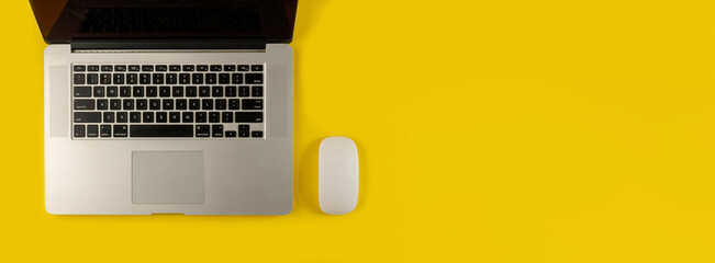 Top view of laptop and mouse on yellow background