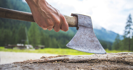Getting wood for fire: Man is holding old axe, tree trunk, countryside