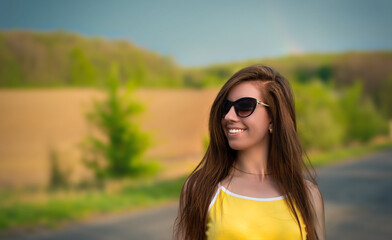 Happy girl warking on nature road. Young woman wearing sunglasses