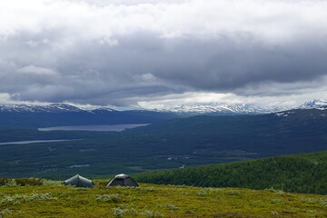 Tents in Swedish hiking trail with view of the mountains with some clouds and snow