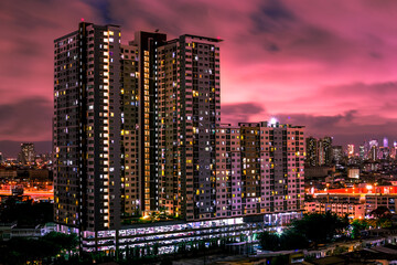 Fototapeta na wymiar The high angle background of the city view with the secret light of the evening, blurring of night lights, showing the distribution of condominiums, dense homes in the capital community