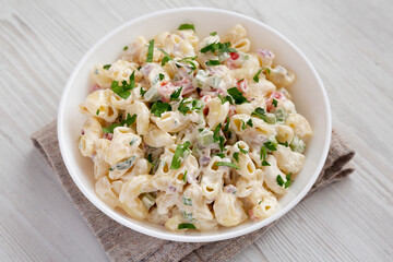 Homemade Macaroni Salad in a white bowl on a white wooden background, side view. Close-up.