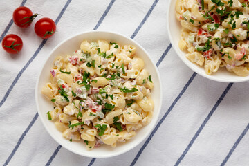 Homemade Macaroni Salad in white bowls, top view. Flat lay, overhead, from above.