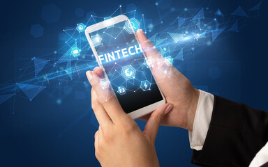 Female hand holding smartphone with FINTECH inscription, modern technology concept