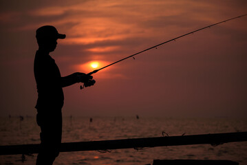 The fisherman silhouette with sunset sky