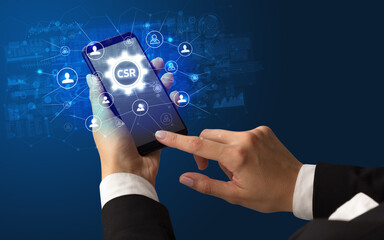 Female hand holding smartphone with CSR abbreviation, modern technology concept