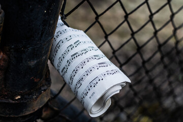 old sheet music jammed into fence outside