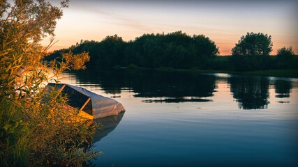 Fototapeta premium River view with sunken fishing boat at sunrise