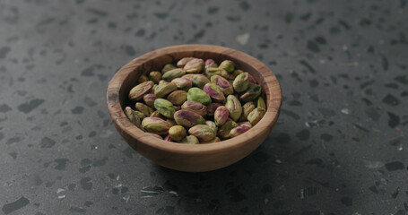 peeled pistachios in olive bowl on terrazzo surface