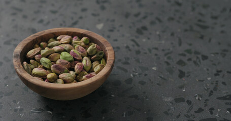 peeled pistachios in olive bowl on terrazzo surface