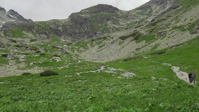 View of Velicka dolina (Velicka valley) in High Tatras mountains, Slovakia. Two hikers walking on a trail. in clean nature and environment. Panning shot