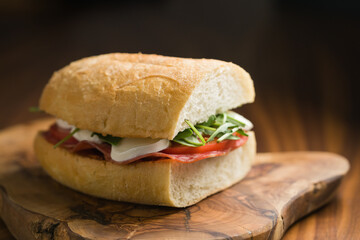 ciabatta sandwich with salami and mozzarella cheese on walnut table