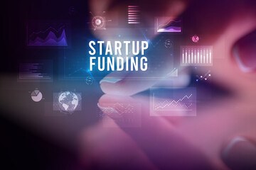 Finger touching tablet with charts and STARTUP FUNDING inscription, business concept