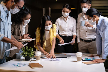 Working late night of Interracial business team wear face mask brainstorm at new normal office