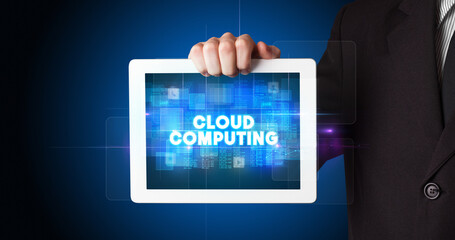 Young business person working on tablet and shows the inscription: CLOUD COMPUTING