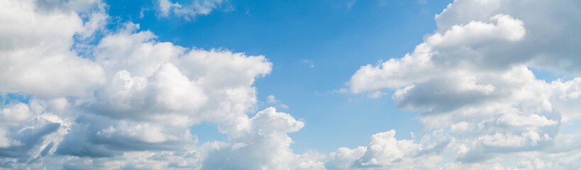Blue skies on a clear day. White cumulus clouds float across the sky.