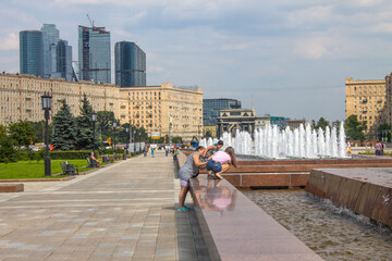 fountain Jets and a view of the modern buildings of Moscow city and Kutuzovsky Prospekt on a summer day against a cloudy sky and a copy space on Poklonnaya hill