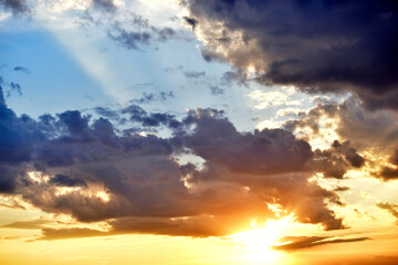 Evening sunset sky with yellow blue clouds and sun rays