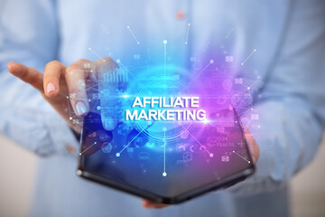 Businessman holding a foldable smartphone with AFFILIATE MARKETING inscription, new business concept