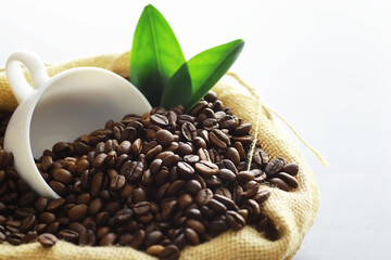 Obraz premium Bag of coffee. Coffee beans roasted on the table. Coffee beans with green leaves for cooking.