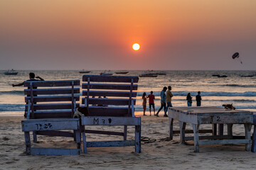 sun loungers on a sandy beach against the sunset