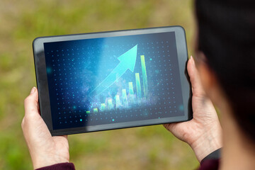 Close-up of a tablet in hands with the image of a graph with an upward arrow. New technologies. Copy space.