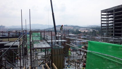 KUALA LUMPUR, MALAYSIA -AUGUST 23, 2019: Construction workers working at the construction site in Malaysia during the daytime. They are required to wearing appropriate safety gear to avoid an accident