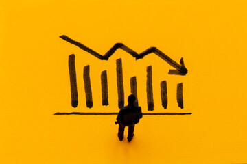 Miniature figurine posed as businessman in front of descending graph, negative performance concept image