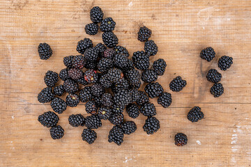 Fototapeta na wymiar Black ripe wild blackberries lie on a wooden table