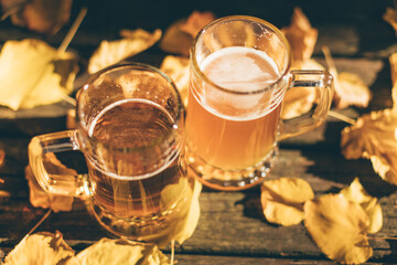 Close-up of two beer glasses on the table against autumn yellow leaves background