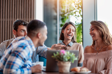 Happy friends talking and laughing in coffee shop
