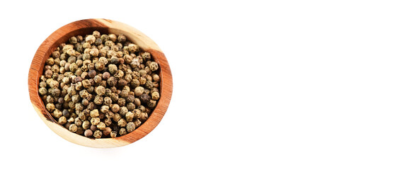 Dried white and green pepper corns in small wooden bowl - view form above isolated on white background space for text right side