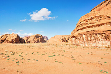 Fototapeta na wymiar Rocky massifs on red sand desert, bright blue sky in background - typical scenery in Wadi Rum, Jordan