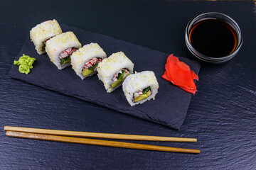 Uramaki sushi rolls with surimi on a black slate