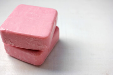 Two bars of pink homemade soap on the white wooden background. Selective focus, copy space