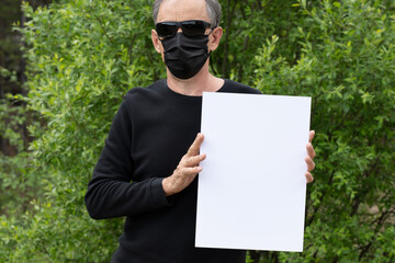 Mockup in the hands of a man. A man in a black medical mask and black glasses on a background of a...