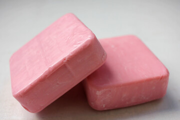 Two bars of pink homemade soap on the white wooden background. Selective focus, copy space